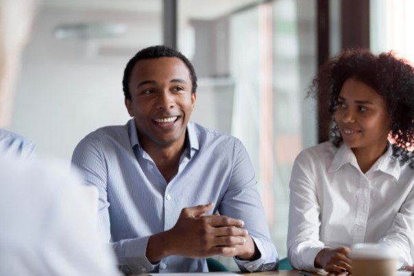 Image shows a smiling man with a woman looking at him smiling