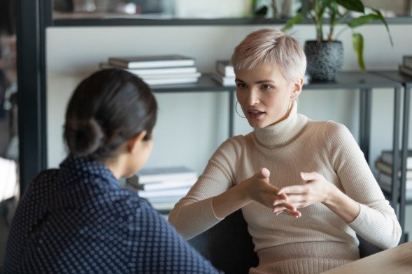 Image shows a young woman with short hair talking to someone