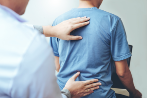 Image shows someone laying two hands on someone's back through a t-shirt