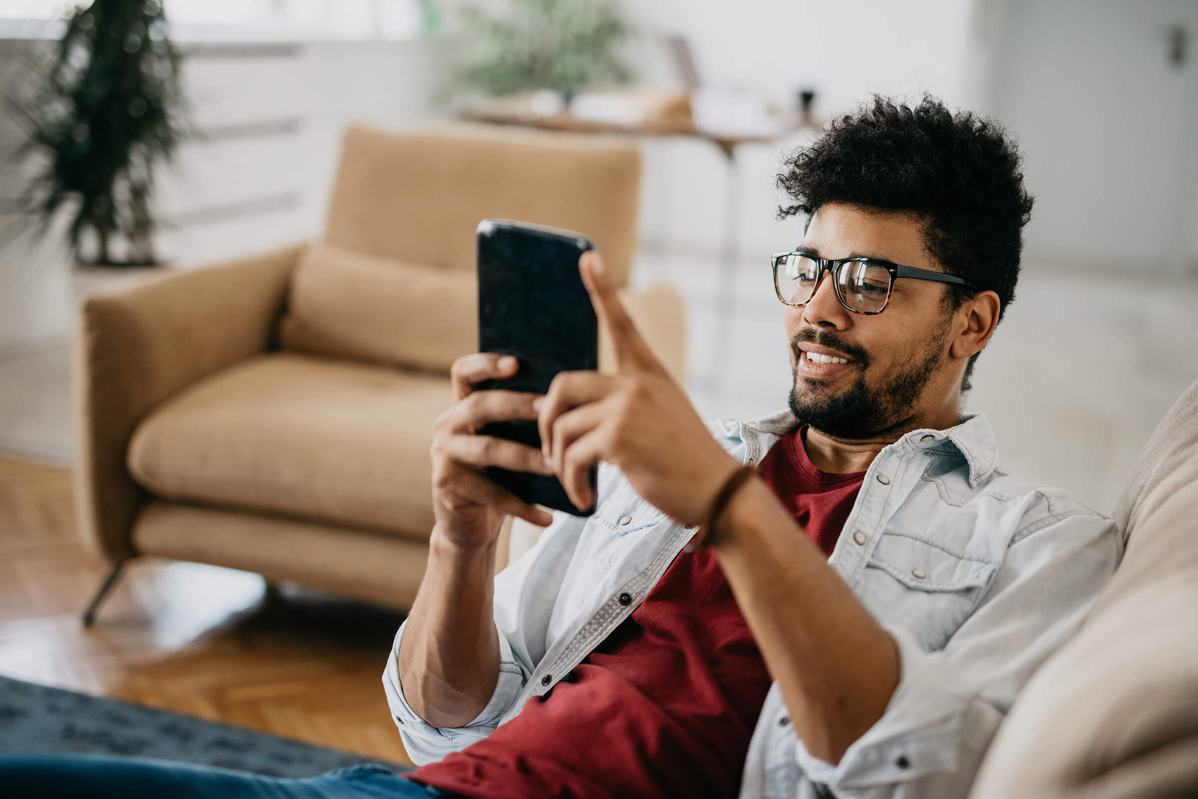 Man laying on a sofa using Symbio on his phone-3