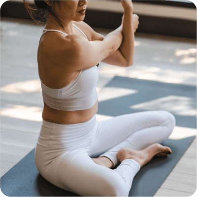 A woman in lotus position stretching her arm