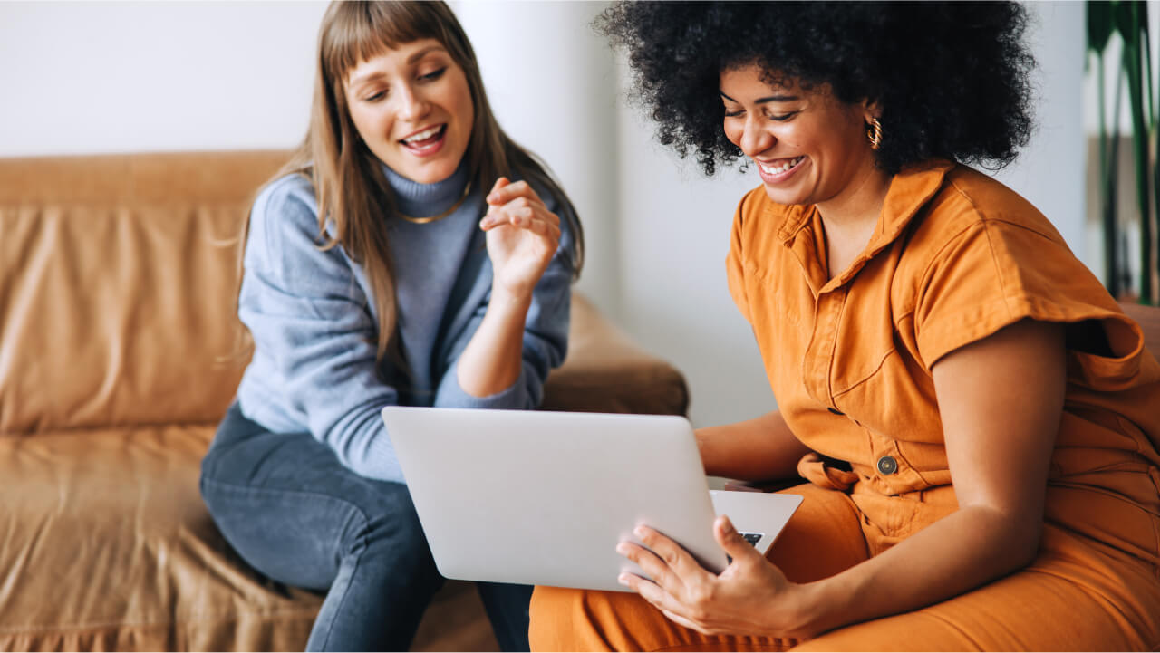 Two woman sitting on sofas with a laptop