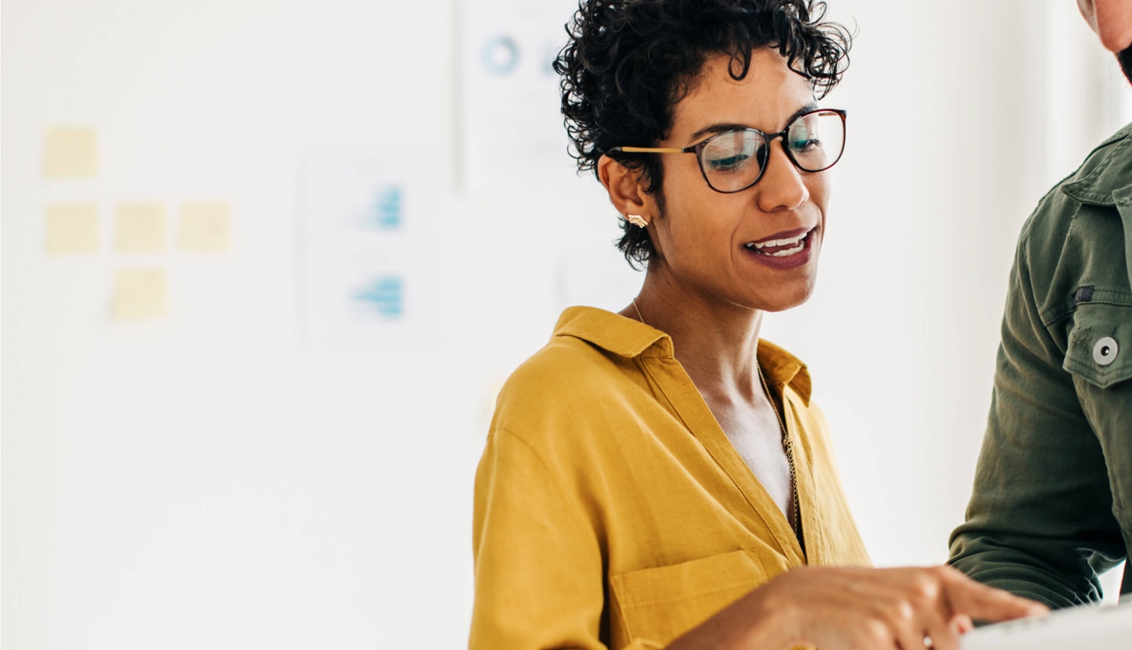 Woman in yellow shirt in an office talking to someone-1