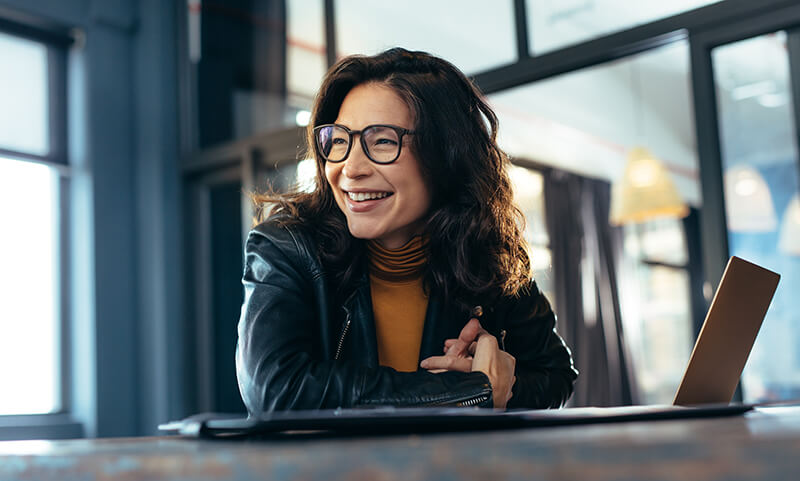 Employee smiling at her desk next to her open laptop