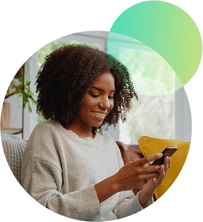 Woman sitting on a sofa smiling at her phone