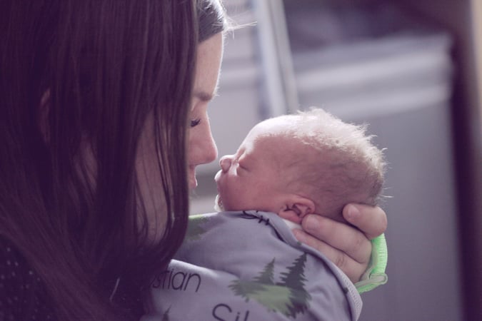 a young woman holding her sleeping baby