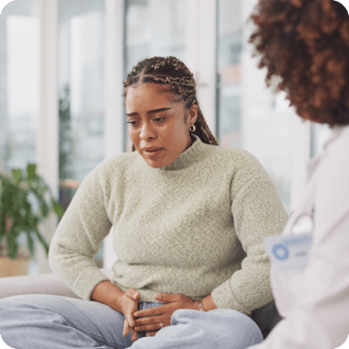 a woman holding her stomach in pain at the doctors