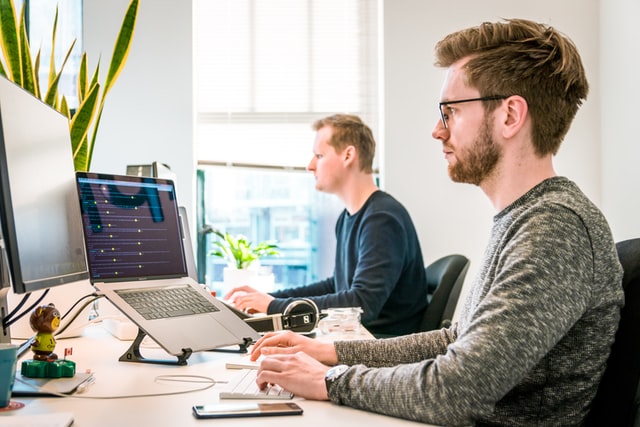 Man works on a computer with a laptop next to him