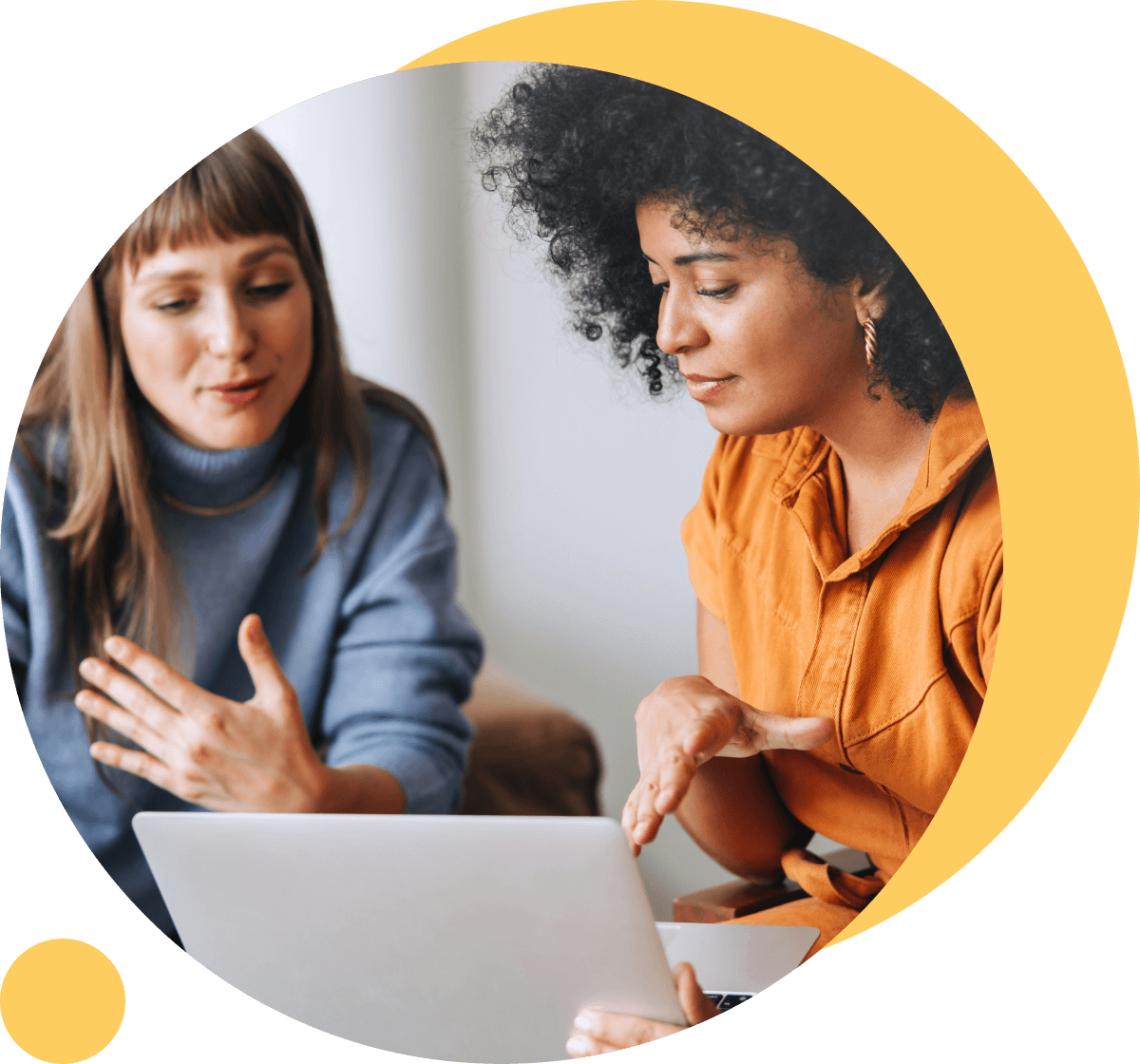 two female colleages talking in front of a laptop